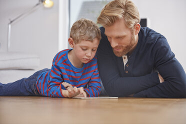 Fathar und Sohn mit digitalem Tablet auf dem Boden liegend - RHF001435