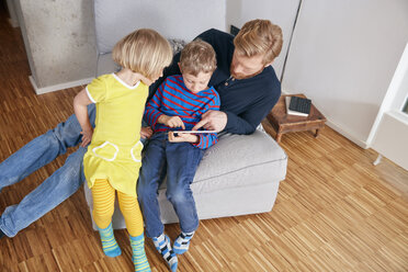 Vater und zwei Kinder benutzen ein digitales Tablet - RHF001440