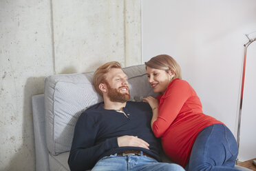 Lächelnder Mann und schwangere Frau auf Couch liegend - RHF001444
