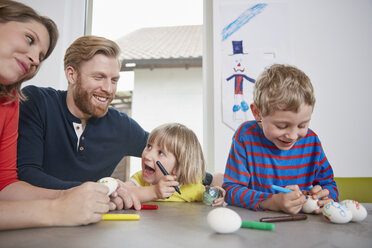 Glückliche Familie beim gemeinsamen Bemalen von Ostereiern - RHF001454