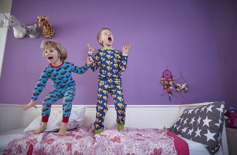 Bruder und Schwester im Schlafanzug beim Herumtollen im Kinderzimmer, lizenzfreies Stockfoto
