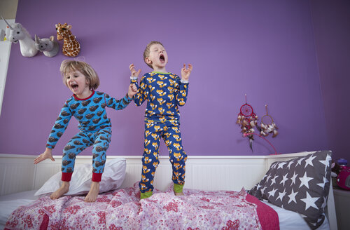 Brother and sister wearing pajamas romping around in children's room - RHF001467