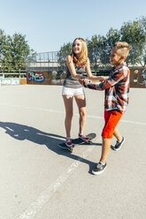 Jugendlicher bringt seiner Freundin das Skateboardfahren bei - AIF000292