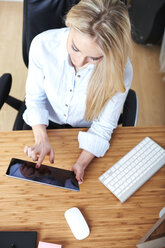 Blond woman sitting at desk using digital tablet - SEGF000495