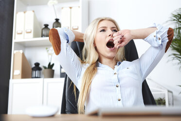 Portrait of blond woman yawning at her desk - SEGF000503