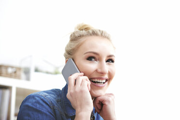 Porträt einer lächelnden blonden Frau, die mit einem Smartphone telefoniert - SEGF000516