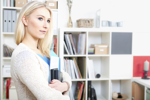 Portrait of blond woman with documents in her home office stock photo