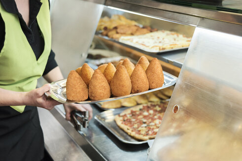 Woman serving fresh arancini, rice croquettes on plate - CSTF001035