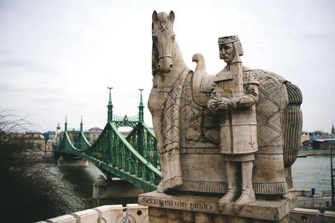 Ungarn, Budapest, Steinskulptur des Heiligen Stephan und Freiheitsbrücke, lizenzfreies Stockfoto