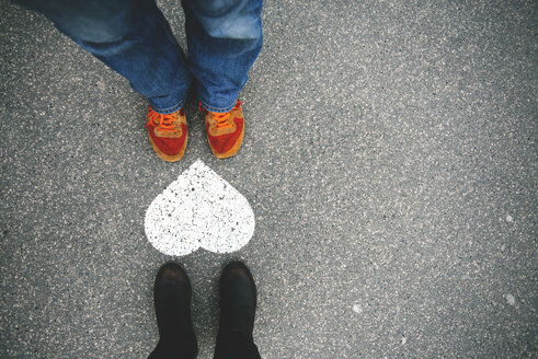 Hungary, Budapest, Feet of man and woman standing by heart on tarmac - GEMF000840