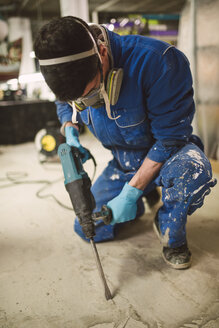 Bricklayer removing irregularities on floor screed with jackhammer - RAEF000988