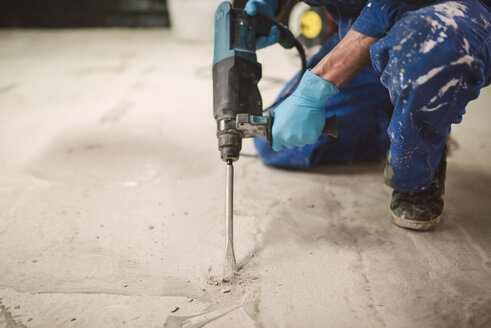 Bricklayer removing irregularities on floor screed with jackhammer - RAEF000991