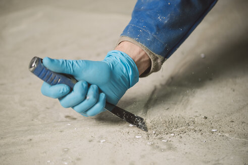 Bricklayer removing irregularities on floor screed with spatula - RAEF000994