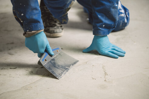 Bricklayer removing irregularities on floor screed with spatula - RAEF000998