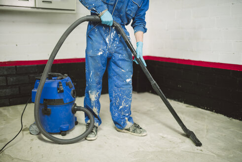 Bricklayer cleaning the floor with an industrial vacuum cleaner - RAEF001000