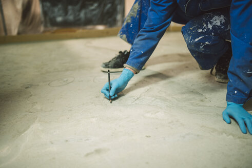 Bricklayer marking irregularities on floor screed - RAEF001002