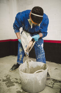 Bricklayer preparing cement, pouring water in bucket - RAEF001008