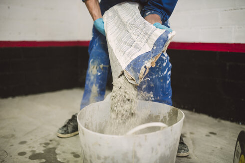 Bricklayer pouring cement powder in bucket - RAEF001009