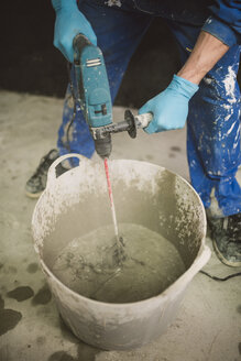 Bricklayer mixing cement in bucket - RAEF001011
