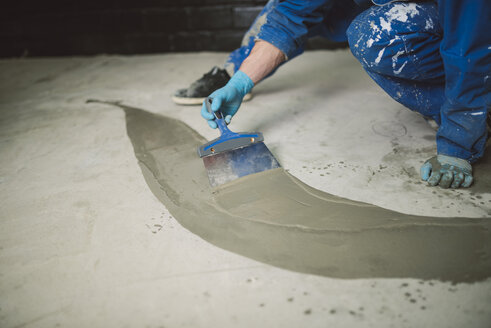 Bricklayer applying wet cement on floor - RAEF001017