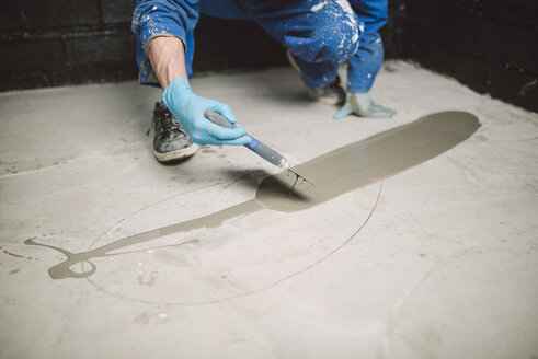 Bricklayer applying wet cement on floor - RAEF001018