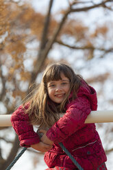 Portrait of smiling little girl climbing on playground equipment - XCF000073