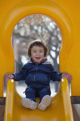 Portrait of laughing little boy sitting on a yellow shute - XCF000074