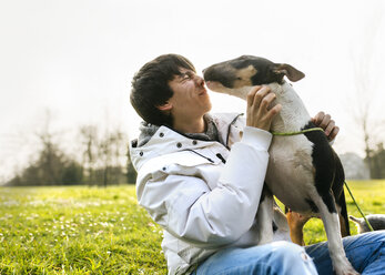 Young man with his bull terrier on a meadow - MGOF001700