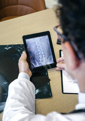 Ein Arzt betrachtet ein Röntgenbild auf einem digitalen Tablet - DAPF000059