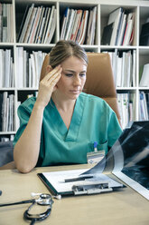 Ärztin beim Betrachten eines Röntgenbildes in ihrem Büro - DAPF000065