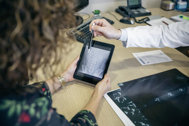 Doctor showing x-ray image on digital tablet to patient - DAPF000072