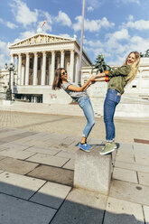 Austria, Vienna, two young women having fun in front of the parliament building - AIF000299
