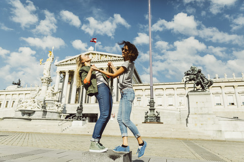 Österreich, Wien, zwei junge Frauen amüsieren sich vor dem Parlamentsgebäude, lizenzfreies Stockfoto