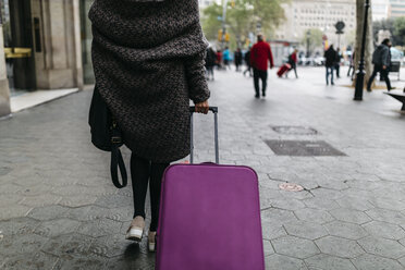 Spain, Barcelona, young woman with suitcase walking in the city - JRFF000512