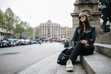 Spain, Barcelona, smiling young woman sitting on stairs in the city - JRFF000519