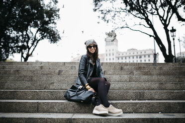 Spain, Barcelona, smiling young woman sitting on stairs - JRFF000520