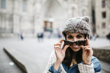 Portrait of smiling young woman putting on sunglasses - JRFF000529