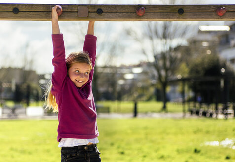 Porträt eines lächelnden kleinen Mädchens, das auf einem Spielplatz spielt - MGOF001707