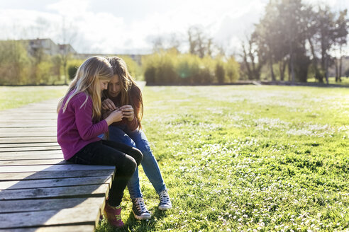 Zwei Mädchen sitzen im Frühling auf einer Promenade - MGOF001710