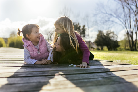 Three smiling girls lying on a boardwalk stock photo