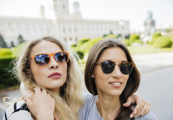 Austria, Vienna, two young women embracing with Museum of Art History in background - AIF000305