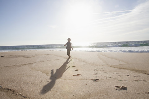 Back view of boy running on the beach at twilight stock photo