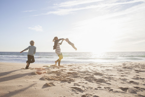 Mother playing with her little sons on the beach stock photo