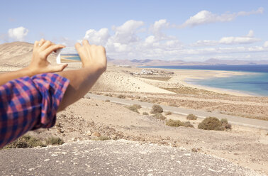 Spanien, Fuerteventura, Jandia, Mann beim Fotografieren an der Küste - MFRF000594