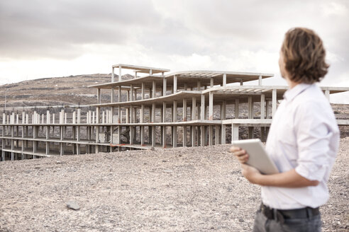 Spain, Fuerteventura, Jandia, architect looking at building shell - MFRF000609