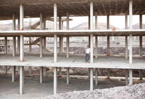 Spain, Fuerteventura, Jandia, architect standing in building shell - MFRF000612