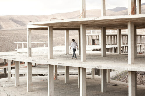 Spain, Fuerteventura, Jandia, architect walking in building shell - MFRF000613