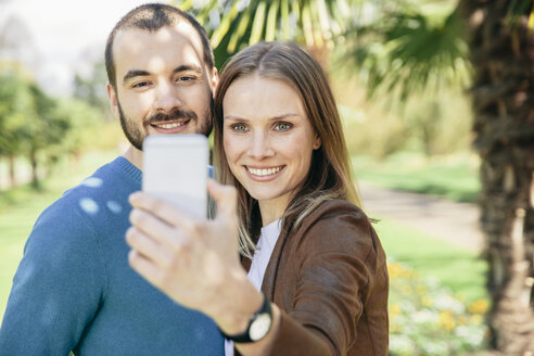 Glückliches Paar macht Selfie mit Smartphone in einem botanischen Garten - MFF002963
