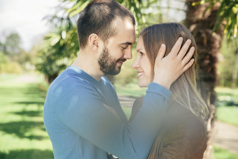 Happy couple face to face in a botanical garden stock photo