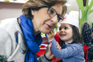 Porträt eines kleinen Mädchens, das das Ohr seiner Großmutter mit medizinischem Spielzeug untersucht - DAPF000088